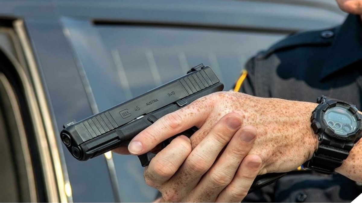 A man in a police officer's uniform holds a Glock G45 pistol