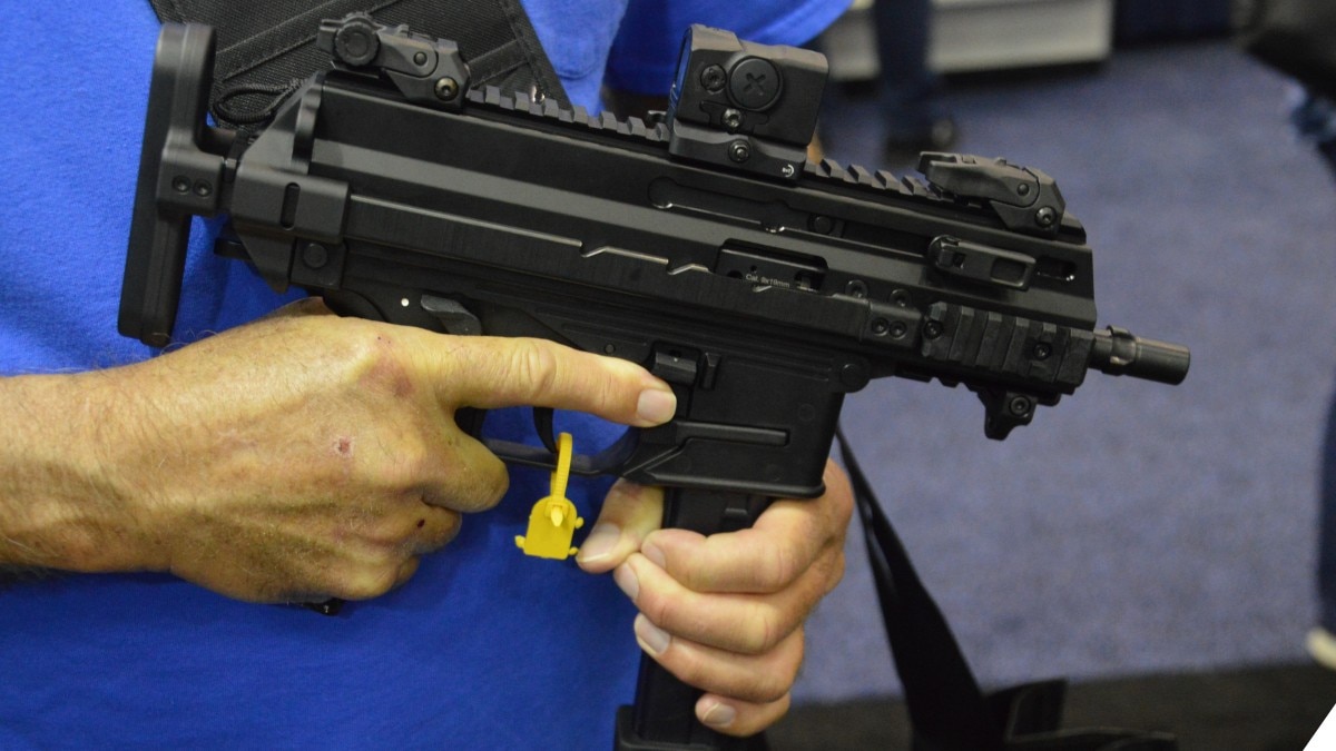 A man in a blue shirt holds a B&T APC9K smg in its compact form