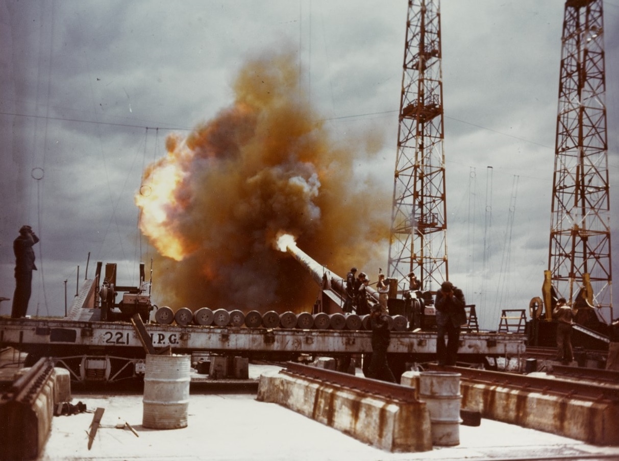 80-G-K-13602 Dahlgren 14 - inch gun fires a test round down range, during World War II. Gun crewmen are covering their ears with their hands for noise and shock protection.